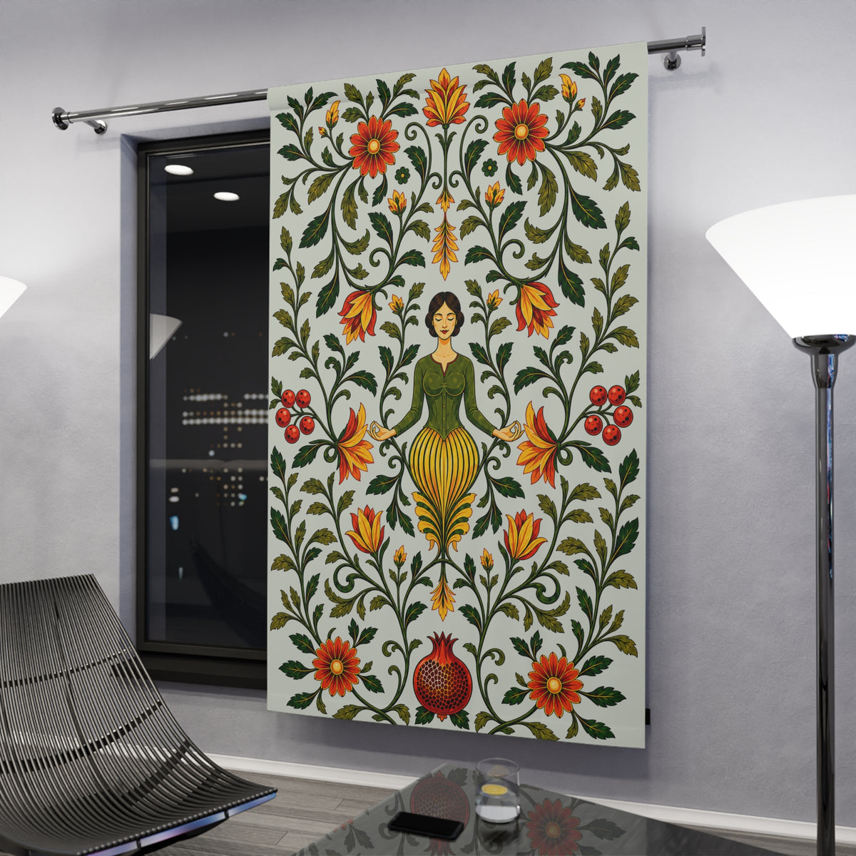A large fabric wall hanging or tapestry displayed in a modern room. The tapestry features a folk-art style design with a central female figure surrounded by symmetrical floral and vine motifs in green, red, orange, and yellow on a light background.