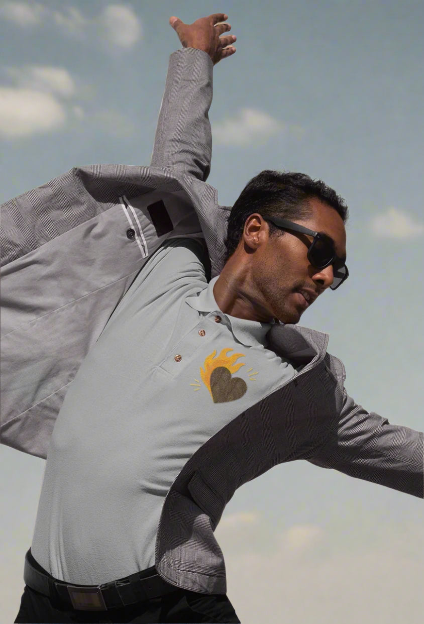 A man wearing a gray jacket with a heart design in polo tee