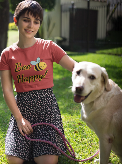 Woman wearing a 'Bee Happy' shirt with a dog on a leash in a grassy area.